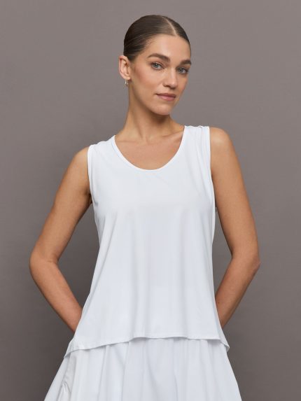 Model wears a loosely fitted round neck white tank top.