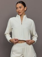 Model wears a cropped white collared activewear jacket.