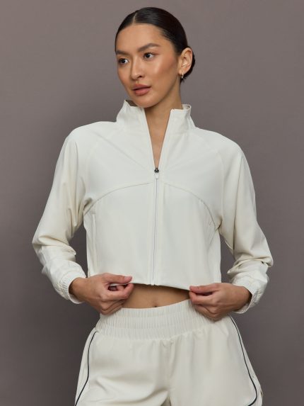 Model wears a cropped white collared activewear jacket.