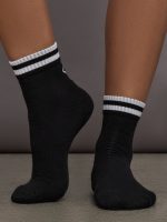 Model wears black athletic sock with contrast stripe patterning.