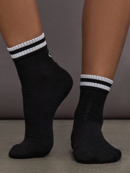 Model wears black athletic sock with contrast stripe patterning.   