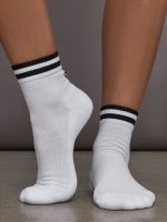 Model wears white athletic sock with contrast stripe patterning.
