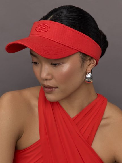 Model wears a bright red visor with Goldbergh logo on front.