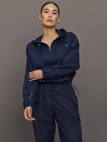 Model wears a navy hooded track jacket.