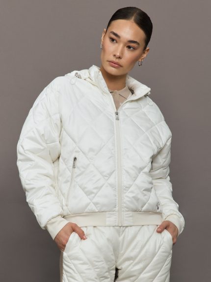 Person wearing a white quilted jacket and pants against a gray background