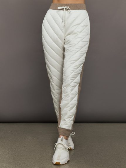 White quilted jogger pants with brown accents on a gray background