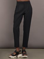 Model wears a pair of mid rise black trousers.