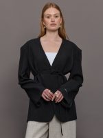 Model wears a wide shoulder black blazer with a deep v neck and drawstring closure.