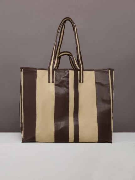 Beige canvas tote bag with black leather bindings, two straps, and an inner pocket.