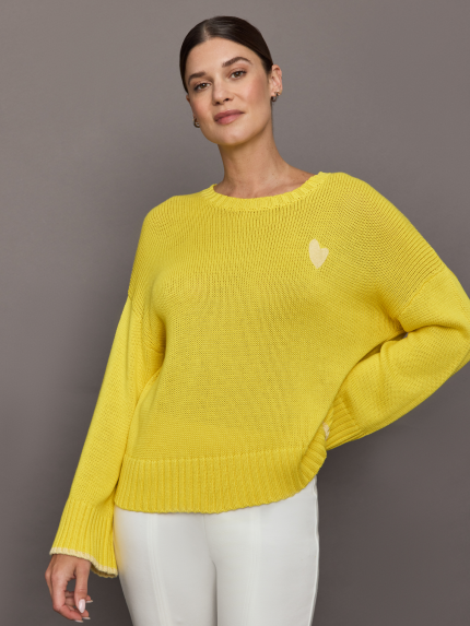 Model wears a sunshine yellow knit sweater with a relaxed fit, featuring a lighter-colored heart detail in the corner.
