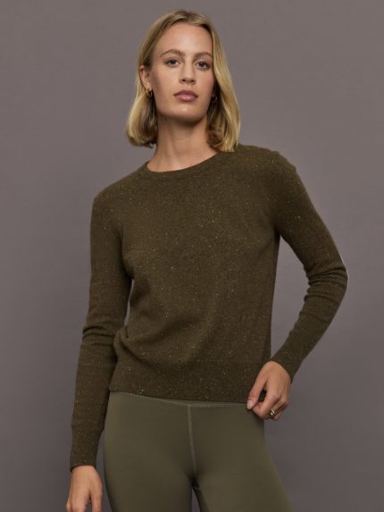 Woman wearing an army green sweater and green leggings against a gray background