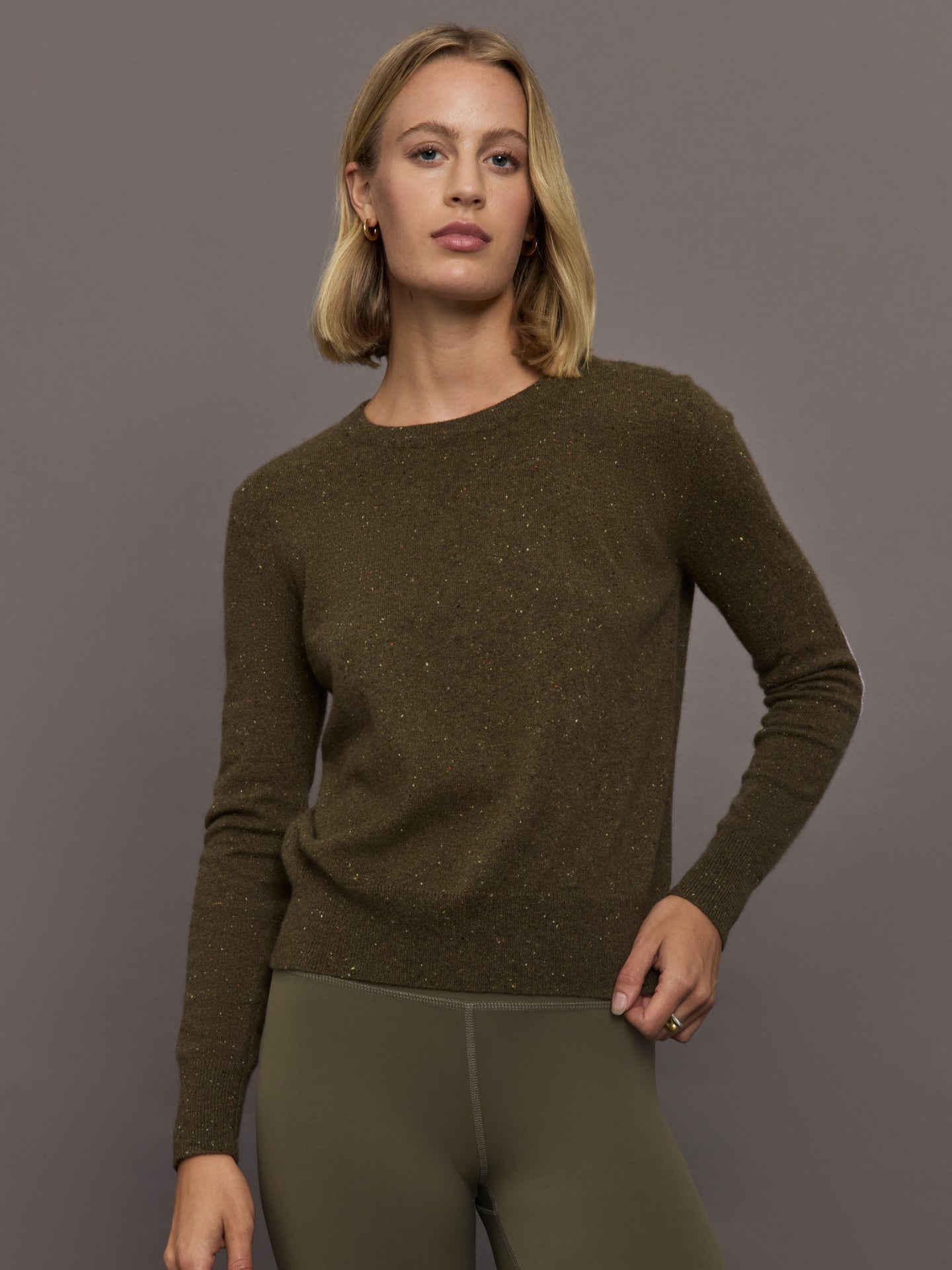 KRRNL-KR253-3347-GRNGRNDRK-Patchwork-Pullover-color-Army-Green_12111-Edit Woman wearing an army green sweater and green leggings against a gray background