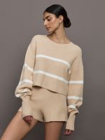 Model wears a boat neck oversized cropped khaki sweater with white horizontal stripes.