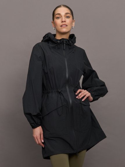 Model is wearing a black raincoat with hood that hits at her mid thigh.