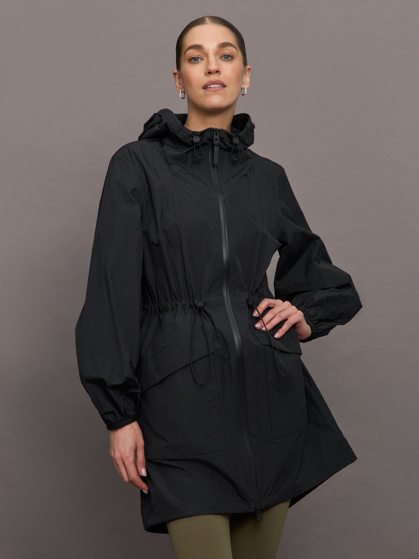 MACK-ALYSTER-BLKBLK-Alyster-color-Black_8244-Edit Model is wearing a black raincoat with hood that hits at her mid thigh.