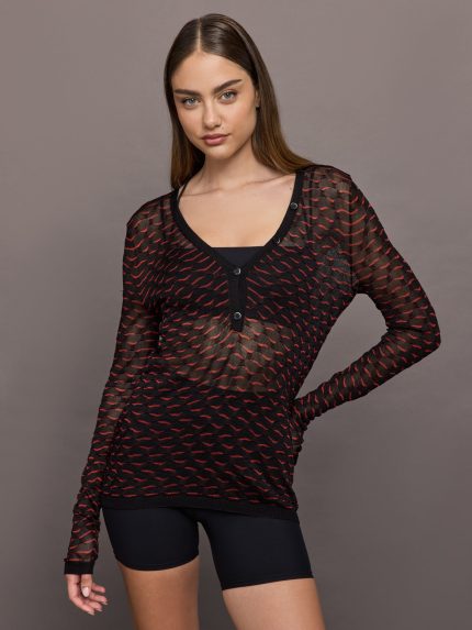 Woman wearing a black and red patterned long-sleeve top against a gray background