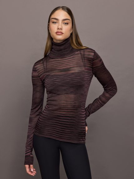 Model wears a striped sheer long sleeve turtleneck with brown and purple tones. 
