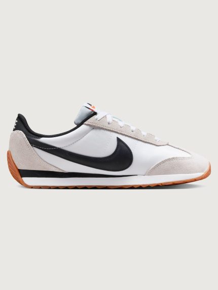 White and black sneaker with a brown sole on a light gray background