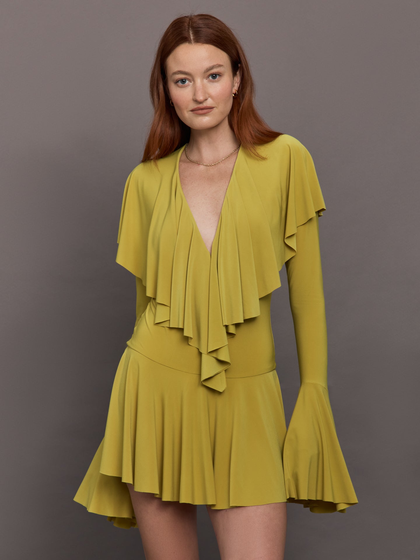 NORMA-KK1253PLO87834-GRNGRNLT-Long-Sleeve-Deep-V-Ruffle-Mini-Dress-color-Asparagus_30682-Edit Model wears long sleeve mini dress in asparagus green with a deep V-neckline and ruffle detailing.