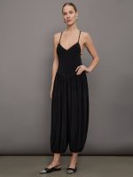 Model wears a v neck, drop waist black jumpsuit with pleated balloon cropped legs.