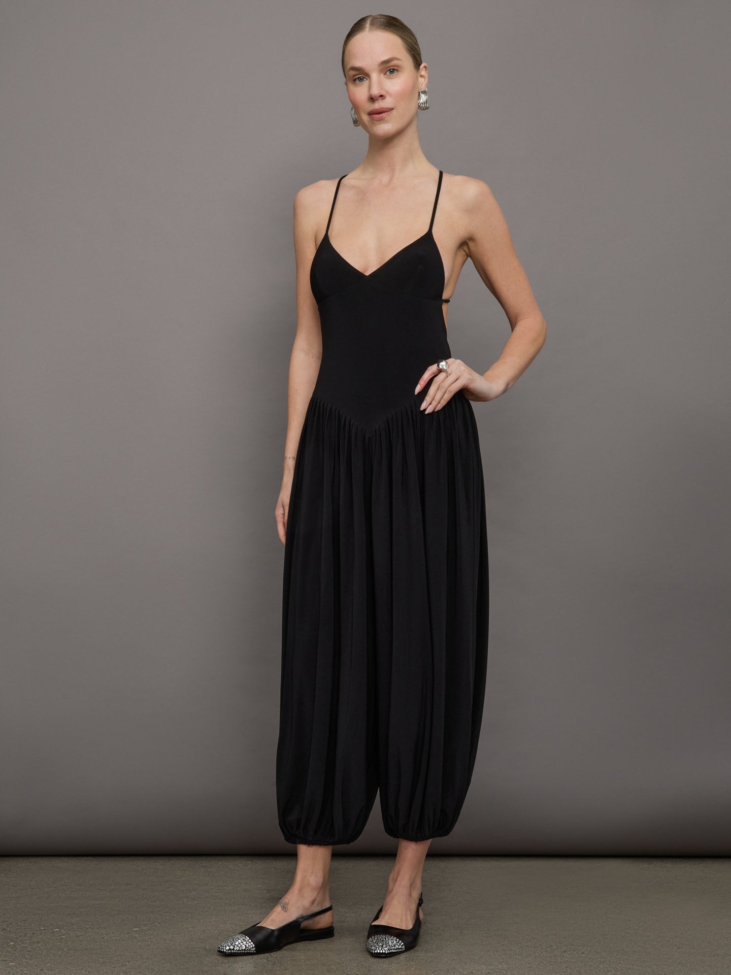 NORMA-KK125JPLO82835-BLKBLK-Kenny-Jumpsuit-color-Black_12637-Edit Model wears a v neck, drop waist black jumpsuit with pleated balloon cropped legs.