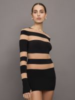 Model wears a long sleeved minidress with thick alternating stripes of black and sheer/mesh.