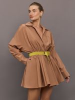 Model wears a soft brown pleated long sleeved dress with a mustard waist tie.