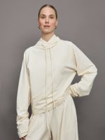 Model wears an oversized cream colored hoodie with extra long drawstrings.
