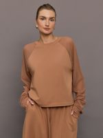 Model wears a light brown long sleeved baseball style loungewear top.