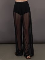 Model wears black high-waisted mesh pants with a wide leg fit.