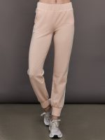 Model wears baby pink jogger pants with side stripes, elastic waistband, and cuffed ankles.