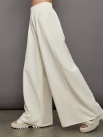 Model wears a pair of oversized wide leg cream colored sweatpants.