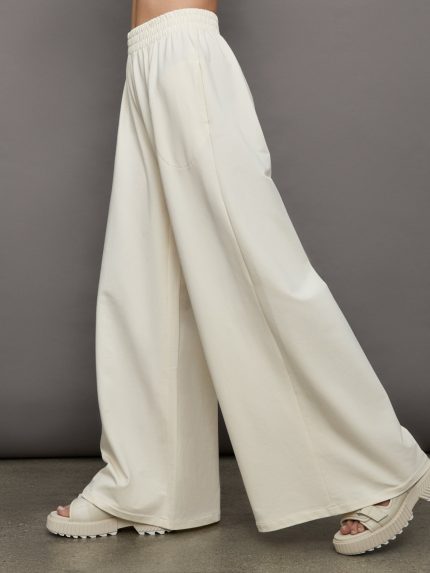 Model wears a pair of oversized wide leg cream colored sweatpants.