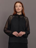 Model wears oversized black hooded top with mesh panel detailing.