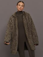 Woman wearing a long, textured coat against a gray background