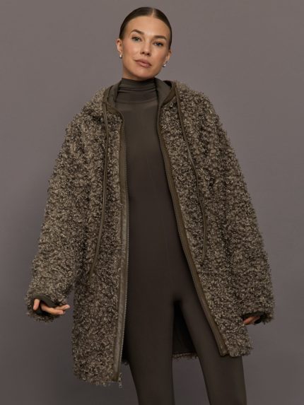 Woman wearing a long, textured coat against a gray background
