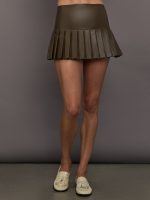Model wears a dark brown pleated miniskirt with built in shorts.