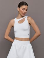 Model wears an asymmetric cut out cropped active tennis tank top in white.