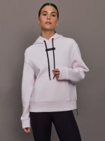 Woman wearing a light purple hoodie with black drawstrings against a gray background