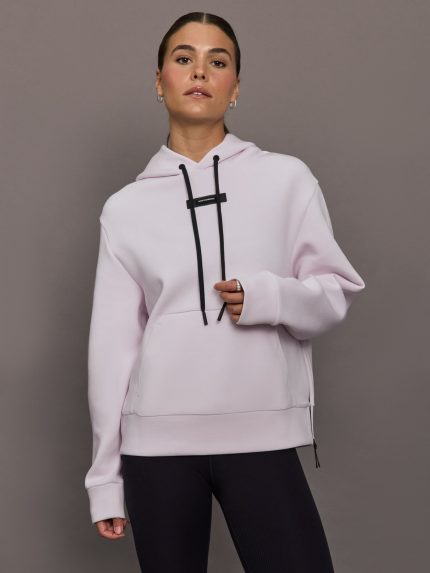 Woman wearing a light purple hoodie with black drawstrings against a gray background