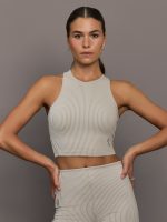 Model wears a high neck sleeveless cropped top in light sandy brown.