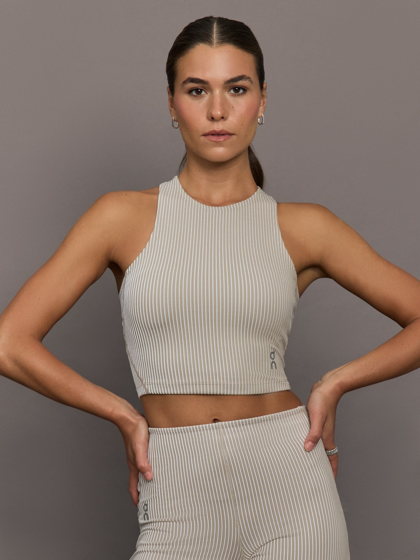 On-1WF30423961-NUDEWHI-All-Day-Ribbed-Crop-color-Desert-White_48926-Edit Model wears a high neck sleeveless cropped top in light sandy brown.