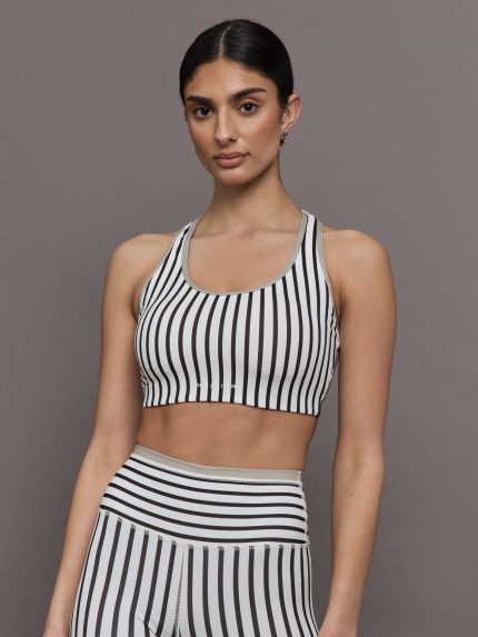 Model wears white with black striped scoopneck sports bra.