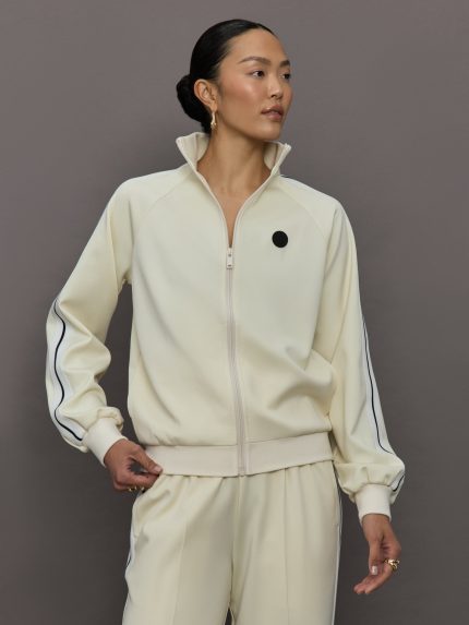 Model wears an off white track jacket with royal blue seam detailing down the sleeves. 