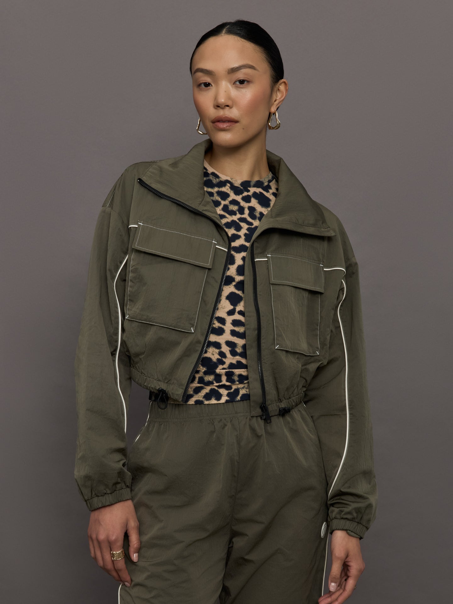 PENAT-251J219-BRWNBRWMED-Recap-Jacket-color-Tarmac-BRown_7299-Edit Model wears an olive colored cropped bomber with symmetrical chest pockets and white seamed detailing.