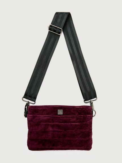Burgundy suede handbag with a black seat belt strap