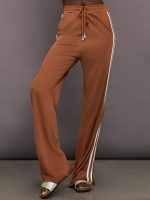 Model wearing light brown track pants with a white stripe down the side.