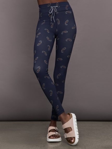 Model is wearing navy blue paisley patterned leggings with striped drawstring.