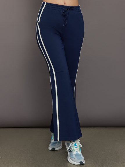 Model wears navy blue flare pants with a mid-rise waist and a fitted silhouette through the hips, gradually flaring out at the legs.