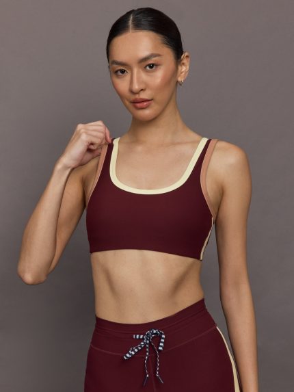 Model wearing a maroon sports bra with a beige trim.